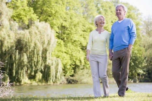 Senior couple enjoying a walk by a pond.