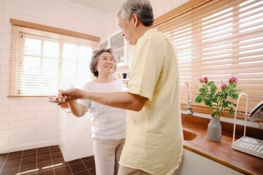 A senior couple dancing in their home.